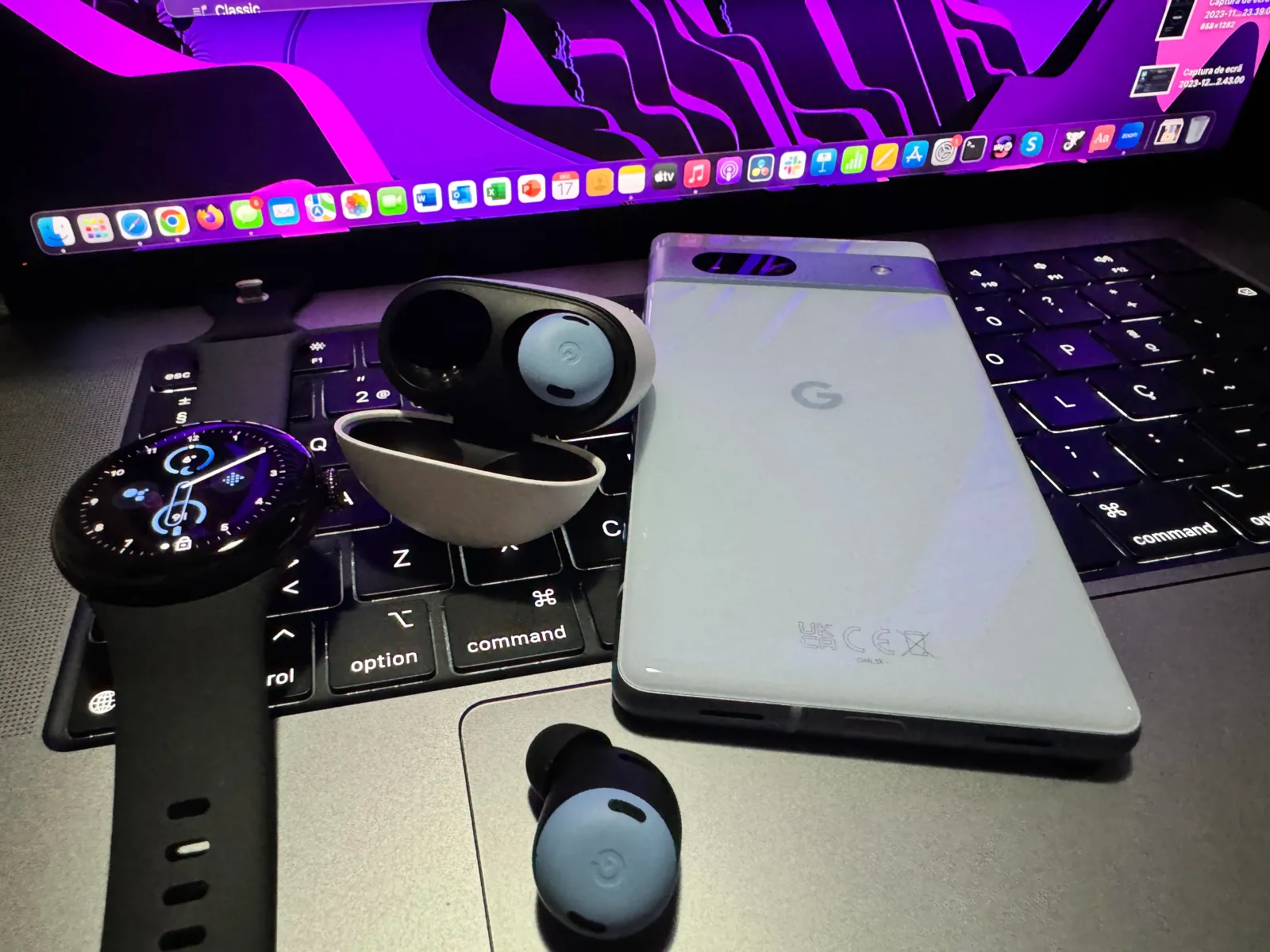 Google Pixel 7a, Pixel Buds Pro e um Pixel Watch 2 em cima do teclado de um MacBook Pro